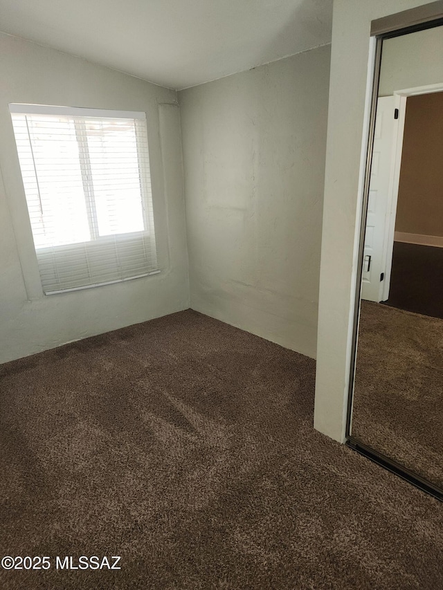 carpeted spare room with vaulted ceiling