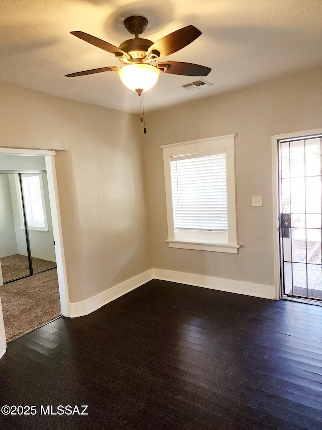 unfurnished room with dark wood-type flooring, a healthy amount of sunlight, and visible vents