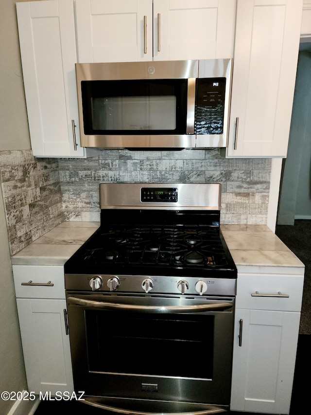 kitchen featuring stainless steel appliances, light countertops, and white cabinets