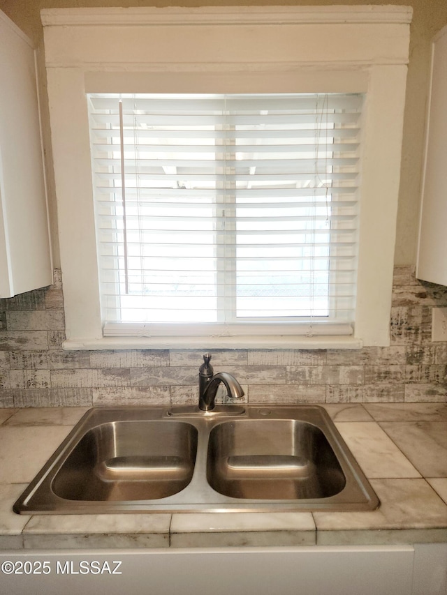 details featuring white cabinetry, a sink, and decorative backsplash