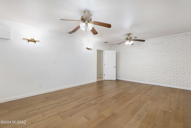 spare room with visible vents, ornamental molding, brick wall, wood finished floors, and baseboards