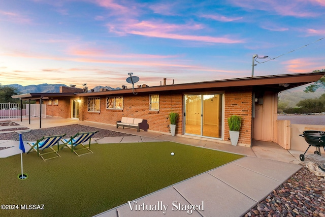 back of property at dusk featuring a patio area, brick siding, and fence