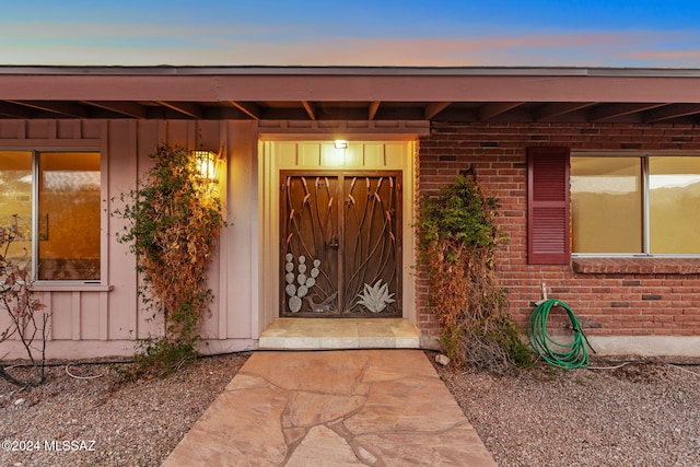 exterior entry at dusk with board and batten siding and brick siding