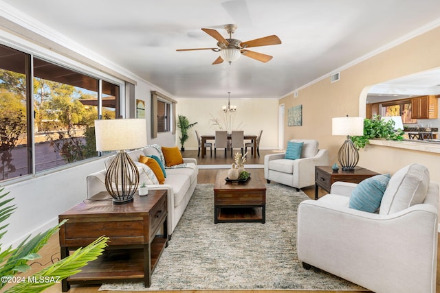 living room with ornamental molding, ceiling fan with notable chandelier, visible vents, and wood finished floors