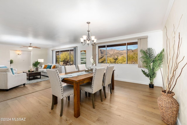 dining area with light wood-style floors, baseboards, ornamental molding, and ceiling fan with notable chandelier