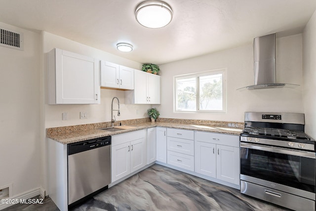 kitchen featuring stainless steel appliances, a sink, visible vents, white cabinetry, and wall chimney exhaust hood