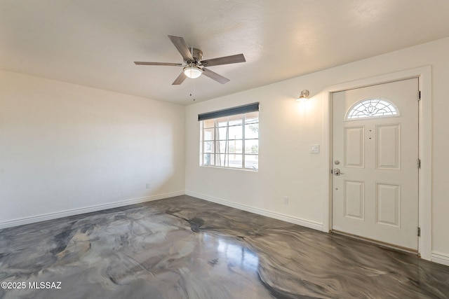 foyer featuring concrete flooring, a ceiling fan, and baseboards