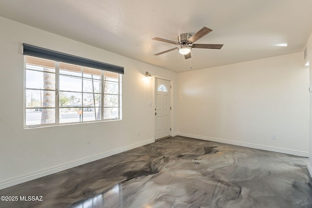 unfurnished room featuring concrete floors, a ceiling fan, and baseboards