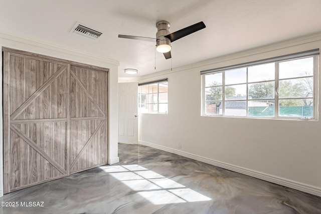 unfurnished bedroom featuring a barn door, baseboards, visible vents, ornamental molding, and finished concrete floors