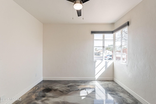 empty room with finished concrete flooring, ceiling fan, baseboards, and a textured wall