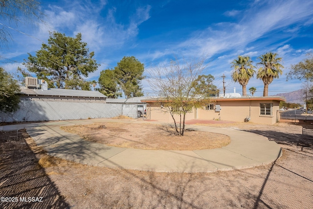 back of house with fence, driveway, and stucco siding