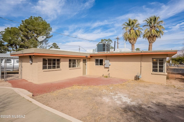 back of property with a patio area, fence, and concrete block siding