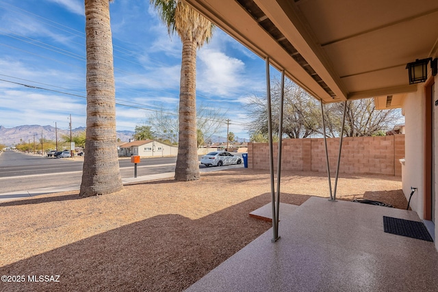 view of patio with fence and a mountain view