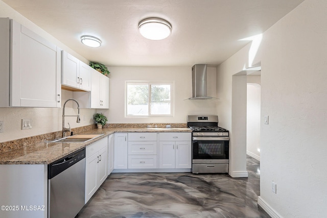 kitchen featuring stainless steel appliances, white cabinetry, a sink, concrete flooring, and wall chimney exhaust hood