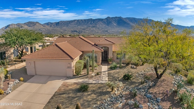 mediterranean / spanish-style house with a mountain view, a garage, a tiled roof, concrete driveway, and stucco siding