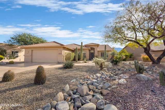 mediterranean / spanish house with concrete driveway, a tiled roof, an attached garage, and stucco siding