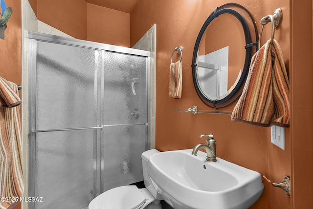 full bath featuring a stall shower, a sink, and toilet