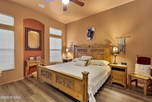 bedroom with a ceiling fan, baseboards, and wood finished floors