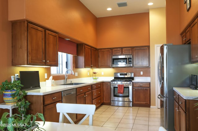 kitchen with visible vents, a towering ceiling, appliances with stainless steel finishes, light countertops, and a sink