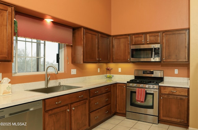 kitchen featuring stainless steel appliances, light countertops, a sink, and light tile patterned floors