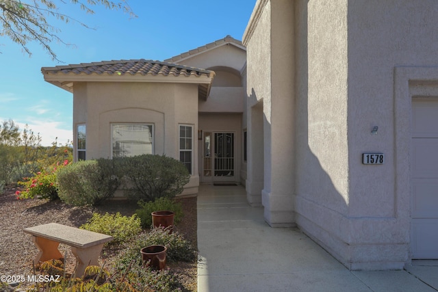 view of exterior entry featuring a tiled roof and stucco siding