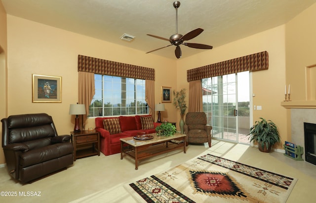 living room with visible vents, a textured ceiling, a tile fireplace, and a ceiling fan