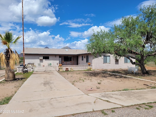 ranch-style house with a porch, a gate, concrete driveway, and stucco siding