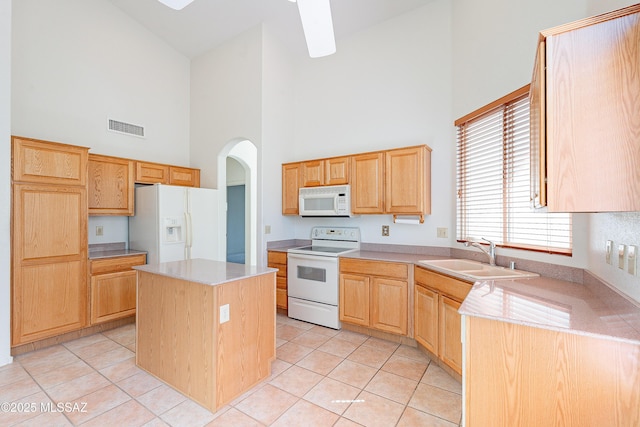 kitchen with a sink, visible vents, white appliances, and light brown cabinets