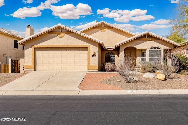 mediterranean / spanish house featuring an attached garage, a tile roof, concrete driveway, and stucco siding