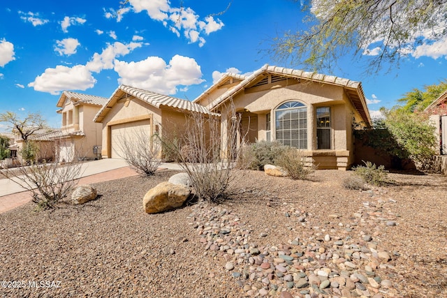 view of front facade with an attached garage, fence, driveway, a tiled roof, and stucco siding