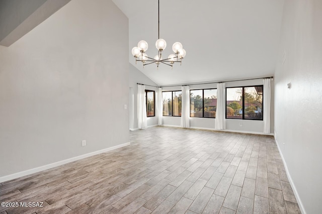 unfurnished living room with high vaulted ceiling, a healthy amount of sunlight, an inviting chandelier, and wood finished floors