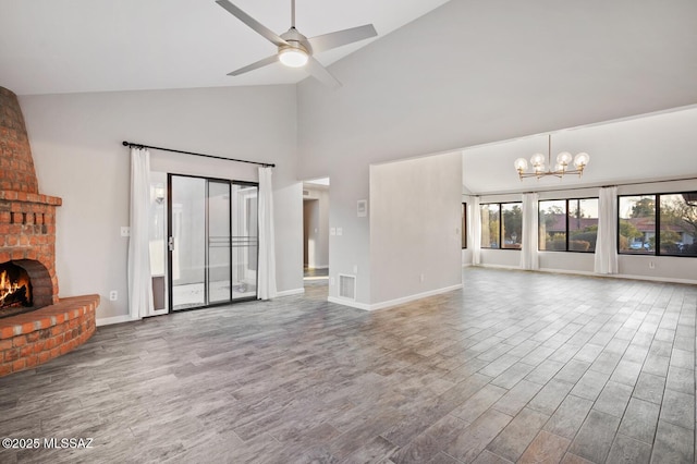 unfurnished living room with ceiling fan with notable chandelier, a brick fireplace, visible vents, and wood finished floors