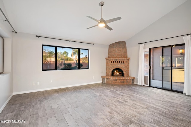 unfurnished living room with a brick fireplace, wood finished floors, a ceiling fan, and baseboards