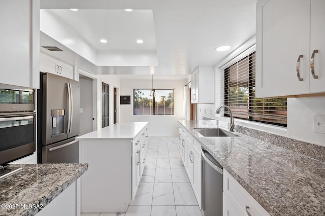 kitchen featuring a center island, marble finish floor, appliances with stainless steel finishes, white cabinetry, and a sink