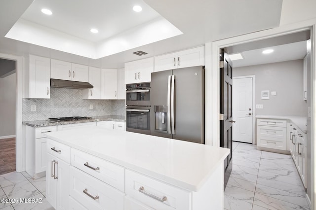 kitchen with visible vents, decorative backsplash, appliances with stainless steel finishes, marble finish floor, and under cabinet range hood