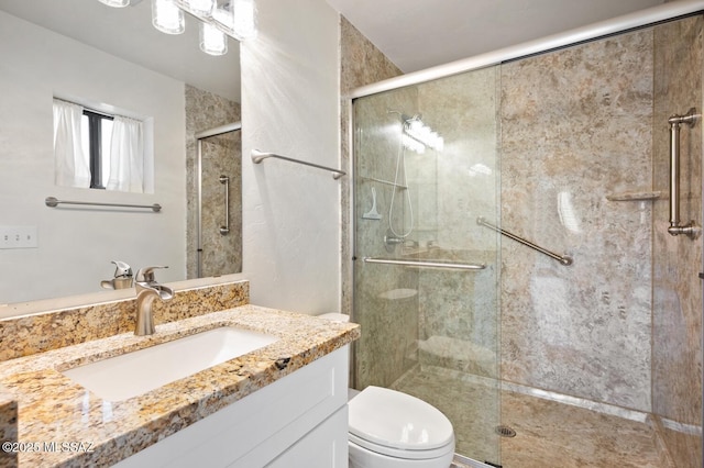 bathroom featuring a shower stall, toilet, and vanity