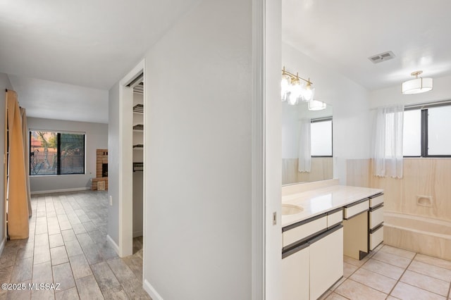 full bathroom featuring a healthy amount of sunlight, a bathtub, visible vents, and vanity