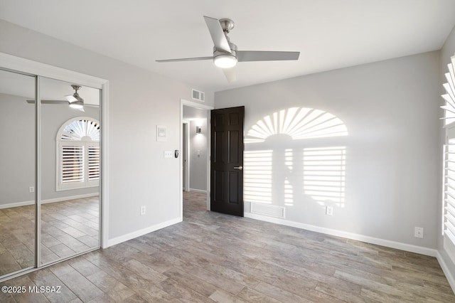 unfurnished bedroom featuring baseboards, a closet, visible vents, and wood finished floors