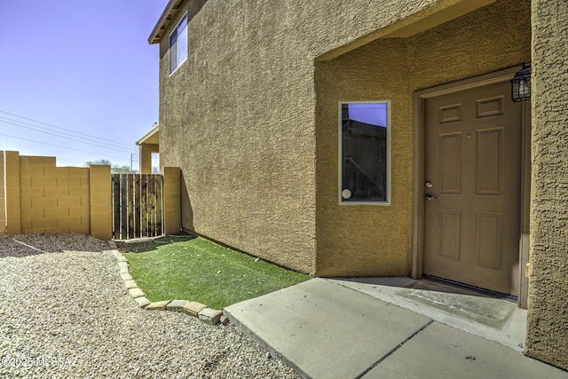 property entrance with fence and stucco siding