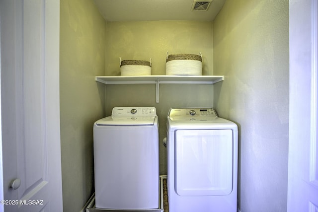 clothes washing area with laundry area, visible vents, and washer and dryer
