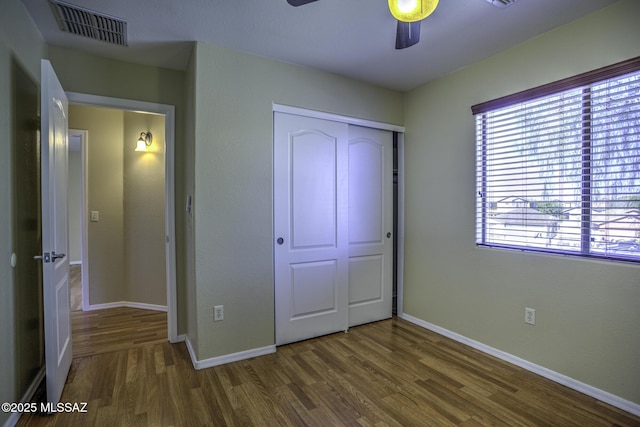 unfurnished bedroom featuring a closet, visible vents, baseboards, and wood finished floors