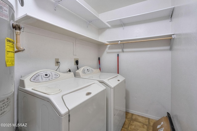 washroom featuring electric water heater, laundry area, baseboards, tile patterned floors, and washing machine and clothes dryer