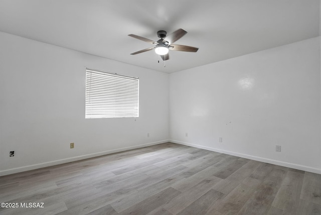 empty room with wood finished floors, a ceiling fan, and baseboards