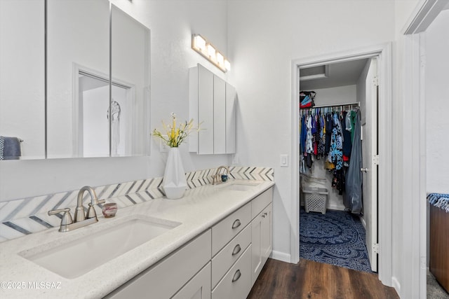 full bath with a walk in closet, wood finished floors, double vanity, and a sink