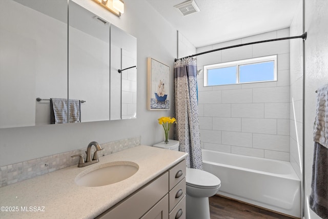 full bath featuring visible vents, shower / tub combo with curtain, toilet, wood finished floors, and vanity