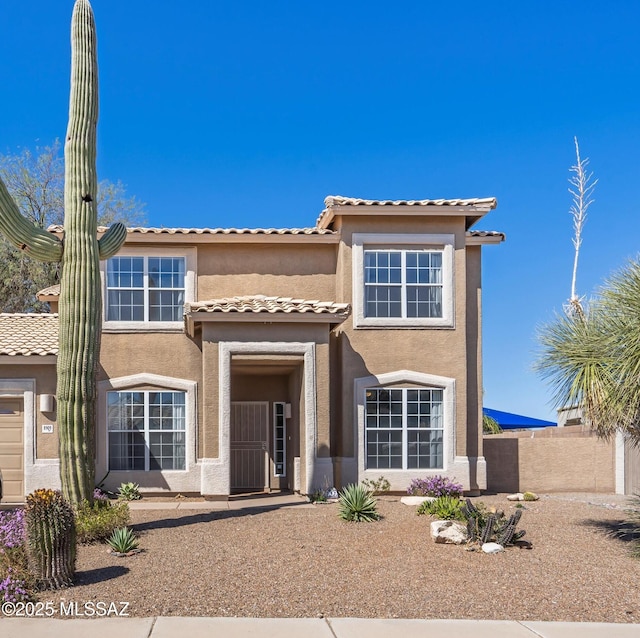 view of front of property with fence, stucco siding, and a tile roof