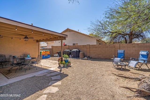 view of yard featuring a patio, ceiling fan, a fire pit, and a fenced backyard