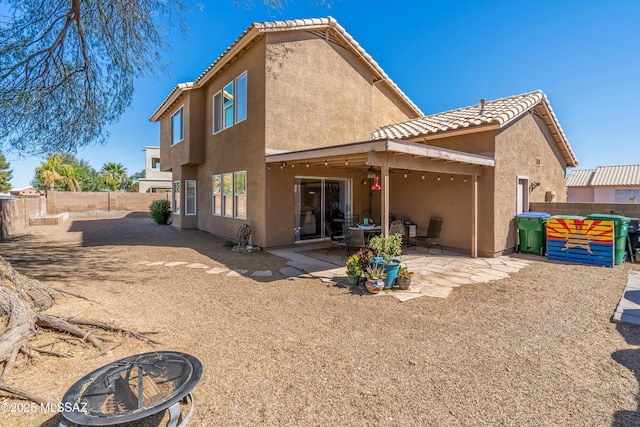 rear view of property featuring a fenced backyard, stucco siding, a fire pit, a tile roof, and a patio area