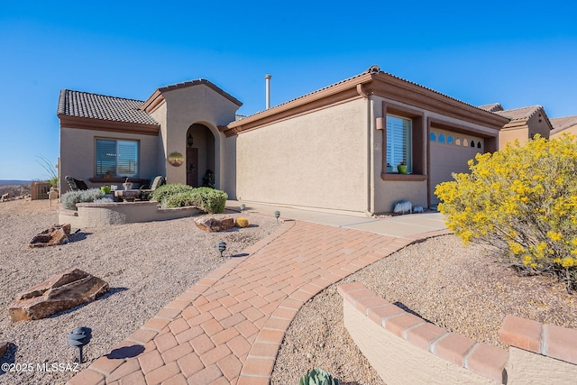 view of front of property with stucco siding, a tiled roof, and a garage