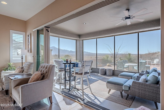 sunroom / solarium with plenty of natural light, a mountain view, and ceiling fan